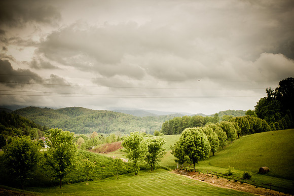 Cloudy Landscape green trees with Hay Bales